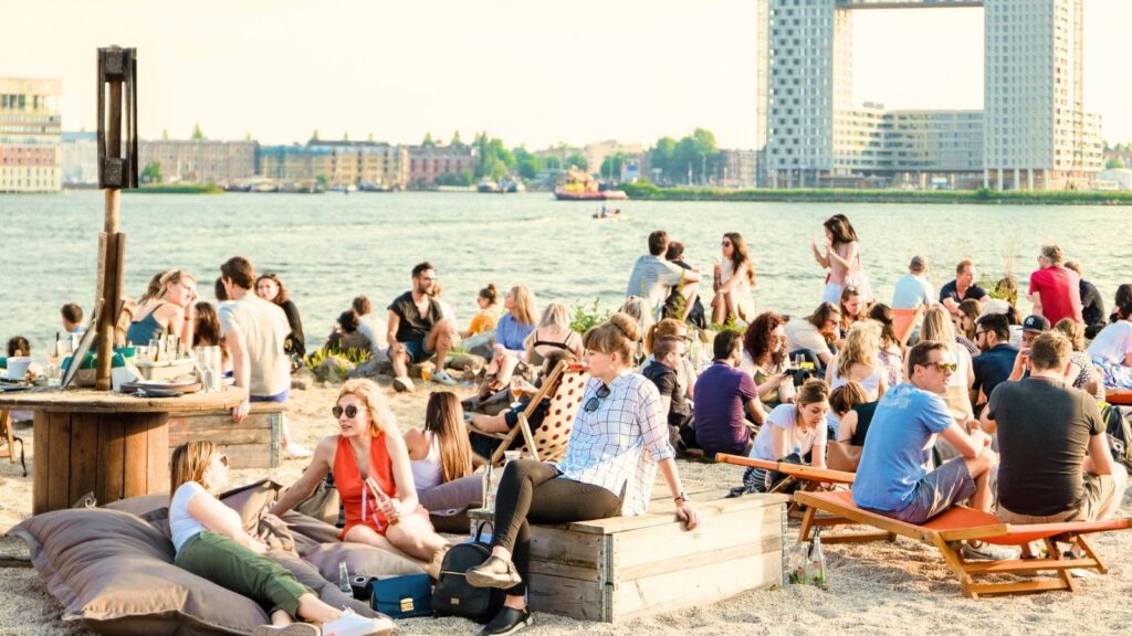 Strand NDSM Amsterdam-Noord met mensen die genieten van het uitzicht op het water.